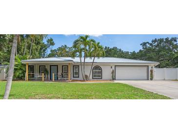 Charming single-story home with lush green lawn, metal roof, and inviting front porch with porch swing at 2820 Whitney Rd, Clearwater, FL 33760