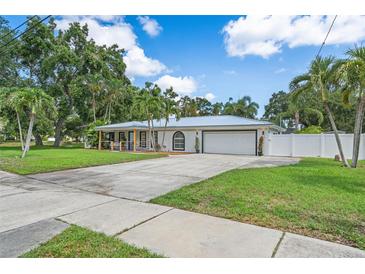 Beautiful single-story home boasts well-manicured lawn, mature trees, and a paved driveway with a two-car garage at 2820 Whitney Rd, Clearwater, FL 33760