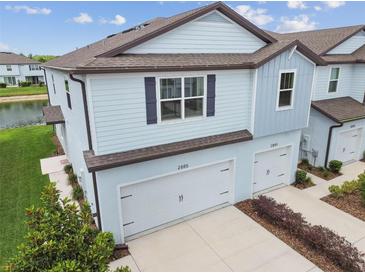 Charming two-story townhome showcasing light blue siding, a well-manicured lawn, and a two-car garage at 2885 Deer Pine Trl, Land O Lakes, FL 34638