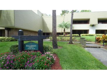 Condominium building exterior with manicured landscaping and signage at Killarney Lodge at 36750 Us 19 N # 09208, Palm Harbor, FL 34684