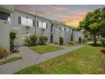 Charming condo complex with lush lawn, sidewalk, and stairs leading to the entrance at 4130 Dolphin Dr, Tampa, FL 33617