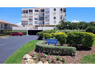 Exterior shot of a white condo building with balconies, lush landscaping, and a community sign at 6218 Palma Del Mar S Blvd # 503, St Petersburg, FL 33715