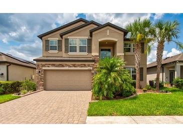 Beautiful two-story home with a brick-accented facade, attached two-car garage, and professionally landscaped front yard at 11035 Sage Canyon Dr, Riverview, FL 33578