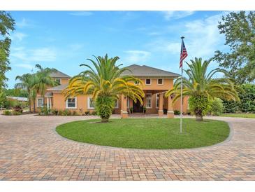 Beautiful custom home featuring lush landscaping, circular driveway and grand entrance with American flag at 11430 Trotting Down Dr, Odessa, FL 33556