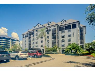 A large building with multiple cars parked out front surrounded by landscaping and clear blue skies at 14820 Rue De Bayonne # 301, Clearwater, FL 33762