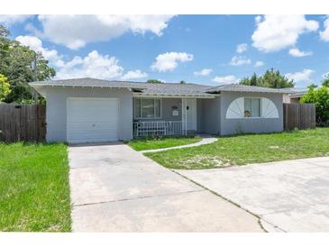 Charming one-story home featuring a quaint front porch, attached garage, and well-maintained lawn at 2809 49Th N St, St Petersburg, FL 33710