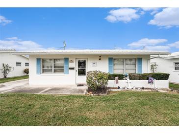 Charming home featuring bright blue shutters, a white exterior, a manicured lawn, and coastal-themed decor at 4325 93Rd N Ter, Pinellas Park, FL 33782