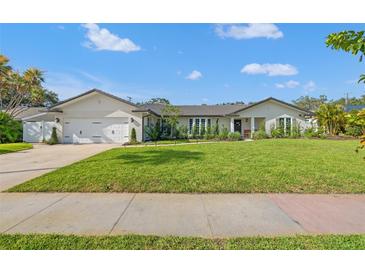 Inviting single-story home featuring a manicured lawn, white brick accents, and a neutral color palette at 460 Althea Rd, Belleair, FL 33756