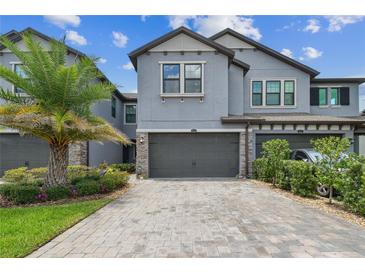 Stylish two-story townhome with a two-car garage, beautiful landscaping, and brick paver driveway at 4653 Ancona Way, Wesley Chapel, FL 33543