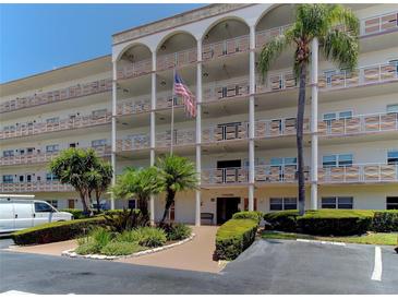 Three story condominium with arched entry and American flag on display at 5603 80Th N St # 103, St Petersburg, FL 33709