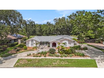 Charming single-story home featuring mature landscaping and a circular driveway for easy access at 13310 Golf Crest Cir, Tampa, FL 33618