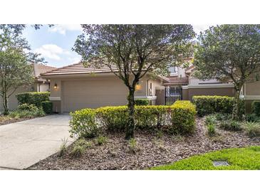 Home exterior with well-kept landscaping, mature trees, and a two-car garage at 17735 Oak Bridge St, Tampa, FL 33647