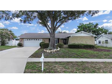Charming single-story home featuring a large front yard with mature landscaping and a two-car garage at 2209 Kingswood Ln, Brandon, FL 33511