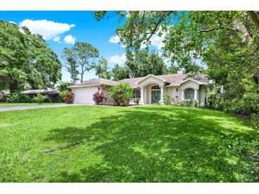 Charming single-story home featuring a lush green lawn, beautiful landscaping, and a two-car garage at 2454 Shadecrest Rd, Land O Lakes, FL 34639