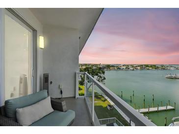 Enjoy stunning waterfront views from this cozy balcony with comfortable seating and modern glass railings at 415 Island Way # 507, Clearwater Beach, FL 33767
