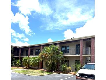 Inviting condo building featuring a blend of stucco and brick facade, enhanced by lush tropical landscaping at 1020 85Th N Ave # 223, St Petersburg, FL 33702