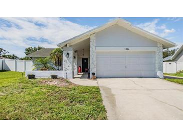 Charming single-story home showcasing a well-maintained front yard and a two-car garage at 1304 Cedar Ct, Tarpon Springs, FL 34689