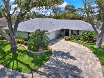Charming one-story home with lush landscaping, a brick driveway, and mature trees at 13186 Linden Place Dr, Seminole, FL 33776