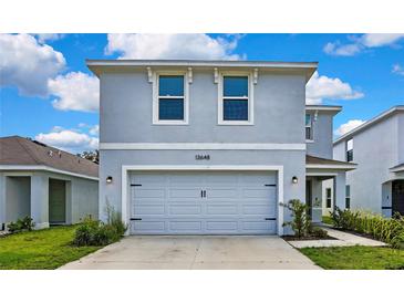 Charming two-story home with a well-maintained lawn and a two-car garage at 13648 Whiskey Daisy Dr, Dade City, FL 33525