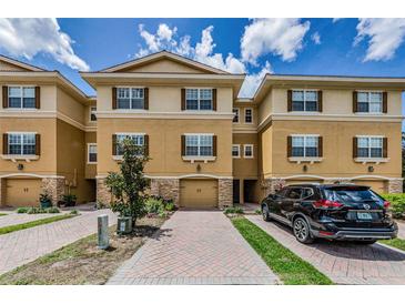Beautiful townhome with tan stucco, brown shutters, and a paver driveway leading to a one-car garage at 5030 Herring Ct, New Port Richey, FL 34652