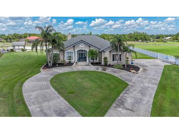 Elegant home with a circular driveway, lush lawn, mature palm trees and landscaped garden beds at 7301 Loghouse Rd, Plant City, FL 33565