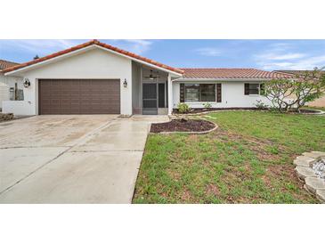 Charming single-story home featuring a brown garage door, red roof tiles and a well manicured front lawn at 734 Flamingo Dr, Apollo Beach, FL 33572