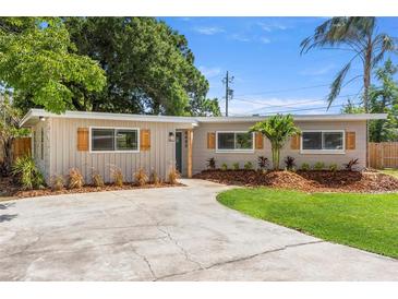 Charming single-story home featuring a well-manicured lawn, gray paint, dark shutters, and a concrete driveway at 8485 Pelican Ln, Seminole, FL 33777