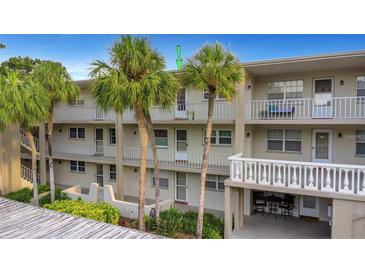 Three-story condo building with palm trees, white railings, and balconies with a peek of an outdoor dining area at 940 Virginia St # 303, Dunedin, FL 34698