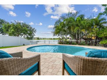 Inviting backyard pool with serene lake view and lush landscaping, perfect for relaxation and outdoor entertaining at 31111 Bridgegate Dr, Wesley Chapel, FL 33545