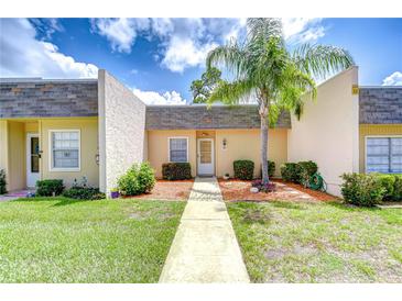 Charming home exterior featuring a well-manicured lawn, walkway, and a beautiful palm tree at 11511 113Th St # 33D, Largo, FL 33778
