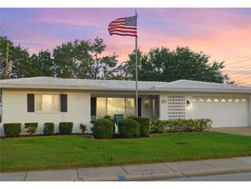 Charming single-story home with lush green lawn and mature landscaping displayed with a picturesque American flag at 4076 Mainlands N Blvd, Pinellas Park, FL 33782
