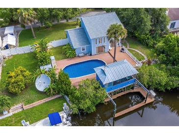 Stunning aerial view of a waterfront home featuring a private pool, boat dock, and lush landscaping at 428 Klosterman W Rd, Palm Harbor, FL 34683