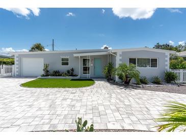 Charming single-story home with a well-manicured lawn, turquoise door, and patterned brick driveway at 6511 10Th N St, St Petersburg, FL 33702