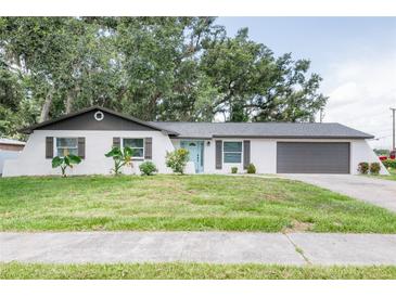 Charming single-story home with a painted brick facade, lush landscaping, and inviting curb appeal at 1008 Shangri La Dr, Seffner, FL 33584