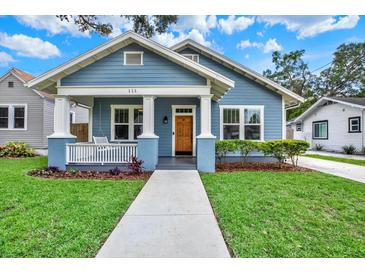 Charming blue home featuring a well-manicured lawn and inviting front porch with columns at 111 E Jean St, Tampa, FL 33604
