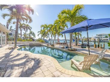 Inviting backyard pool area surrounded by lush palm trees, with waterfront access and comfortable lounge chairs at 11160 8Th E St, Treasure Island, FL 33706