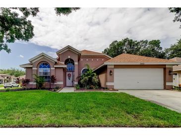 Charming single-story home featuring arched windows, lush landscaping, and an attached two-car garage at 28826 Windover St, Wesley Chapel, FL 33545