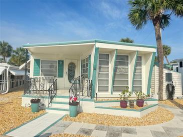 Charming mobile home featuring colorful trim, a welcoming front entrance, and a well-maintained landscaped yard at 4851 W Gandy Blvd # B7L36, Tampa, FL 33611