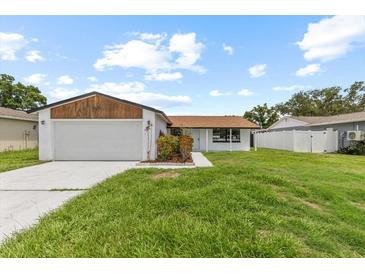 Charming single-story home with a well-maintained lawn, mature trees, and an attached two-car garage at 6370 Elmhurst Dr, Pinellas Park, FL 33782