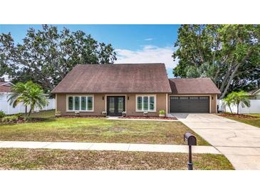 Charming single-story home with a well-maintained front yard, double door entry, and attached garage at 7206 Timber Ct, Tampa, FL 33625