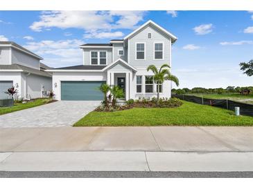 Charming two-story home featuring manicured landscaping, a paved driveway, and a teal garage door at 1583 Running Tide Pl, Sarasota, FL 34240