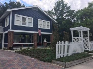 Charming two-story home with a brick foundation, white picket fence and luscious green landscaping at 4106 N Central Ave, Tampa, FL 33603