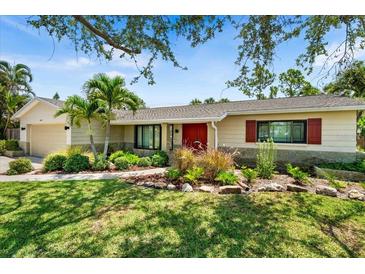 Charming single-story home boasts a well-manicured lawn, mature trees and plants, and a welcoming red front door at 4739 114Th N St, St Petersburg, FL 33708