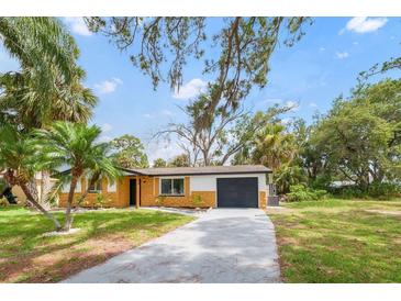 Charming single-story home featuring a gray driveway and tropical landscaping at 5614 Bay Boulevard, Port Richey, FL 34668