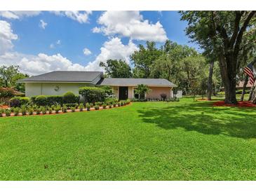 Beautifully landscaped front yard with lush green lawn and manicured hedges and flowerbeds enhance this home's curb appeal at 126 Holly Tree Ln, Brandon, FL 33511