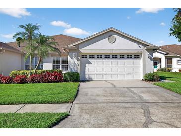 Charming single-story home featuring a two-car garage and lush landscaping at 1822 Sassafras Dr, Wesley Chapel, FL 33543
