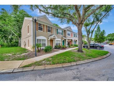 Charming townhome featuring neutral stucco and wood accents, with mature trees surrounding the property at 5502 Carrollwood Key Dr, Tampa, FL 33624