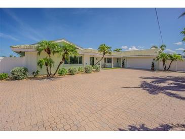 Charming single-story home with a brick driveway, attached garage, and well-maintained landscaping with palms at 5950 Bikini N Way, St Pete Beach, FL 33706