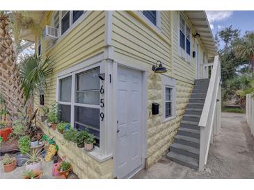 Charming yellow exterior of building with white trim and front door and stairway entrance at 659 26Th S Ave, St Petersburg, FL 33705