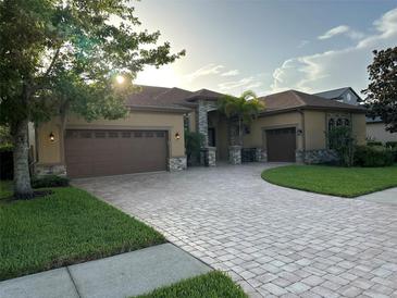 Stunning home with a paver driveway, mature landscaping, and a three-car garage at 1008 Arista Blvd, Valrico, FL 33594